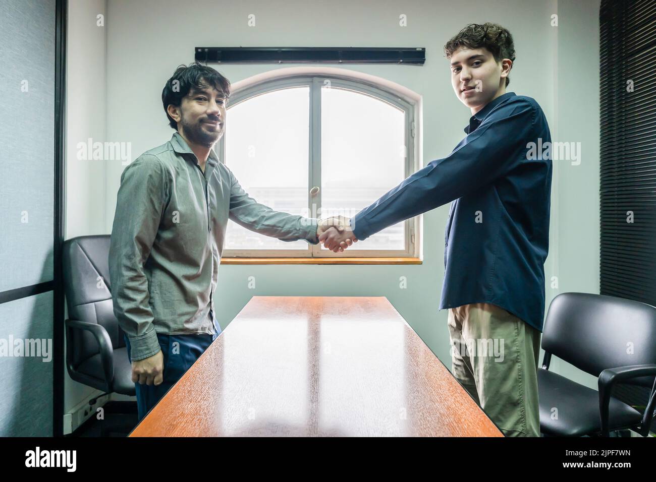 Office men shaking hands looking at the camera. Concept of deal, agreement Stock Photo
