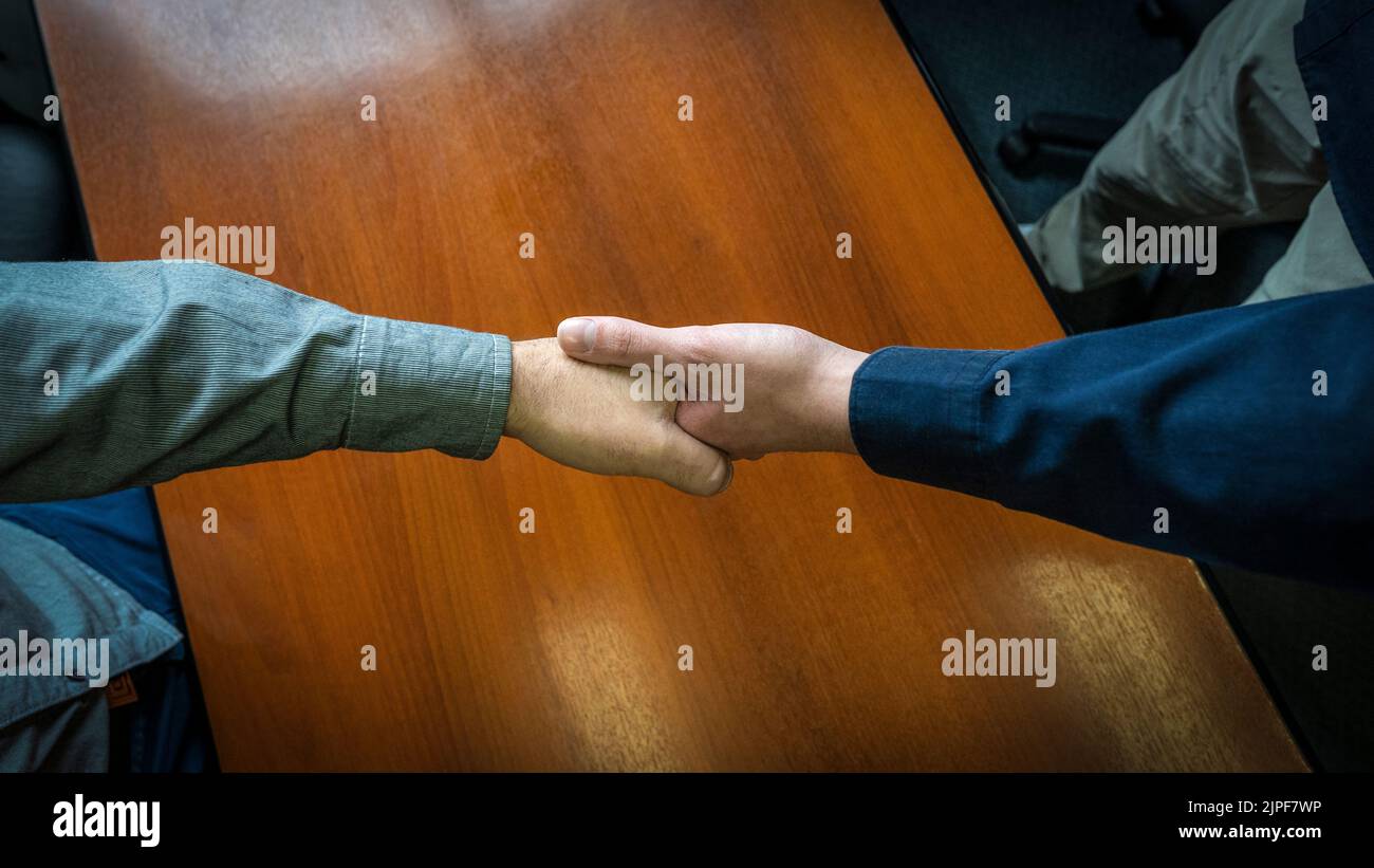 Close-up overhead shot of two men shaking hands. Concept of deal, agreement Stock Photo