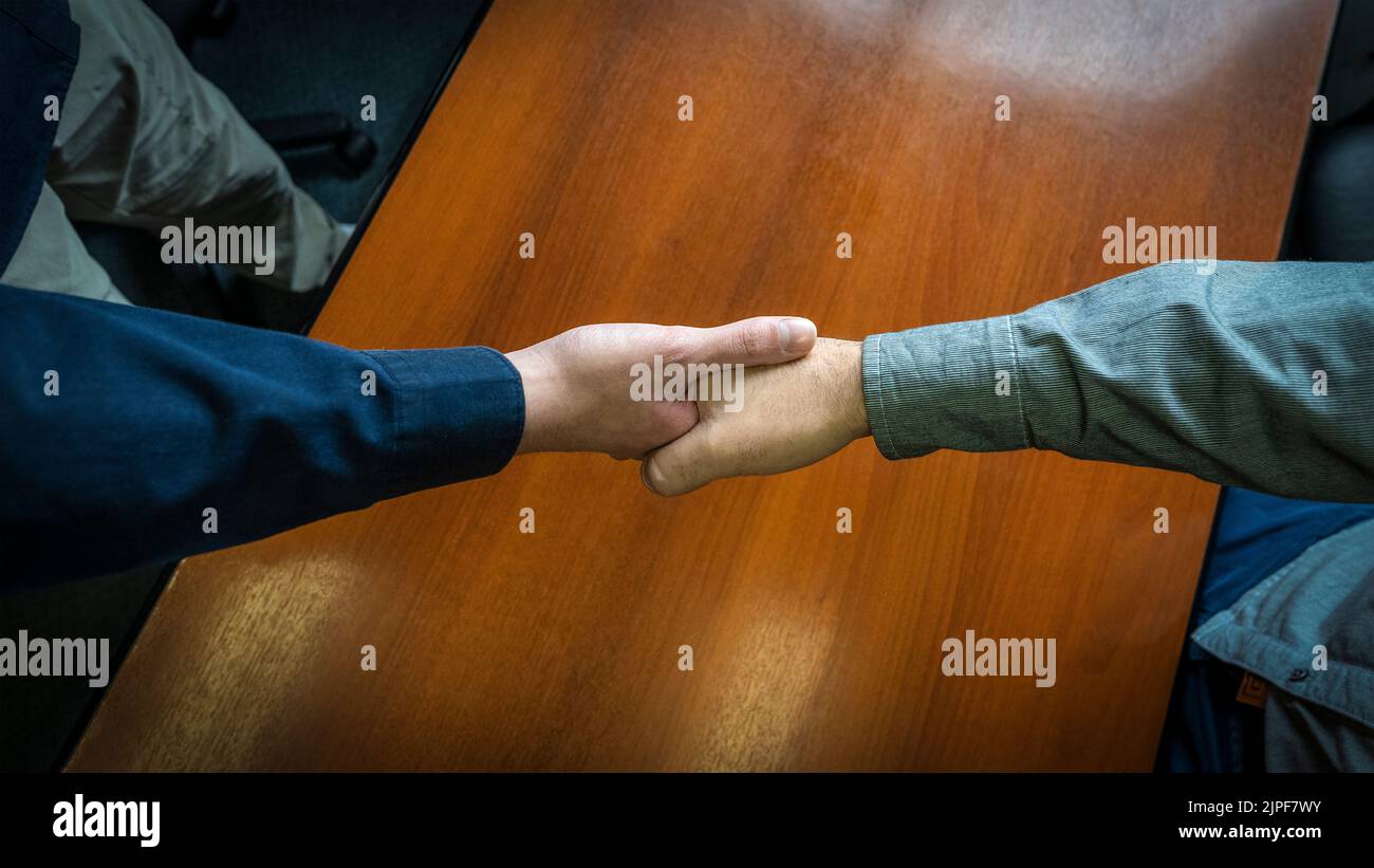 Close-up overhead shot of two men shaking hands. Concept of deal, agreement Stock Photo