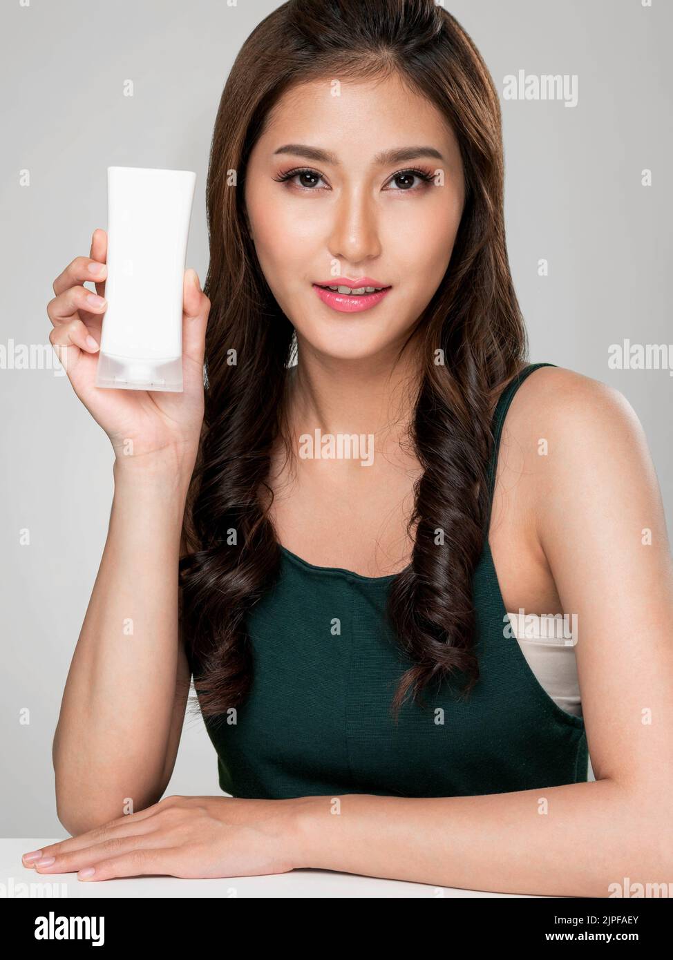 Closeup ardent woman smiling holding mockup product for advertising text place, light grey background. Concept of healthcare for skin, beauty care Stock Photo