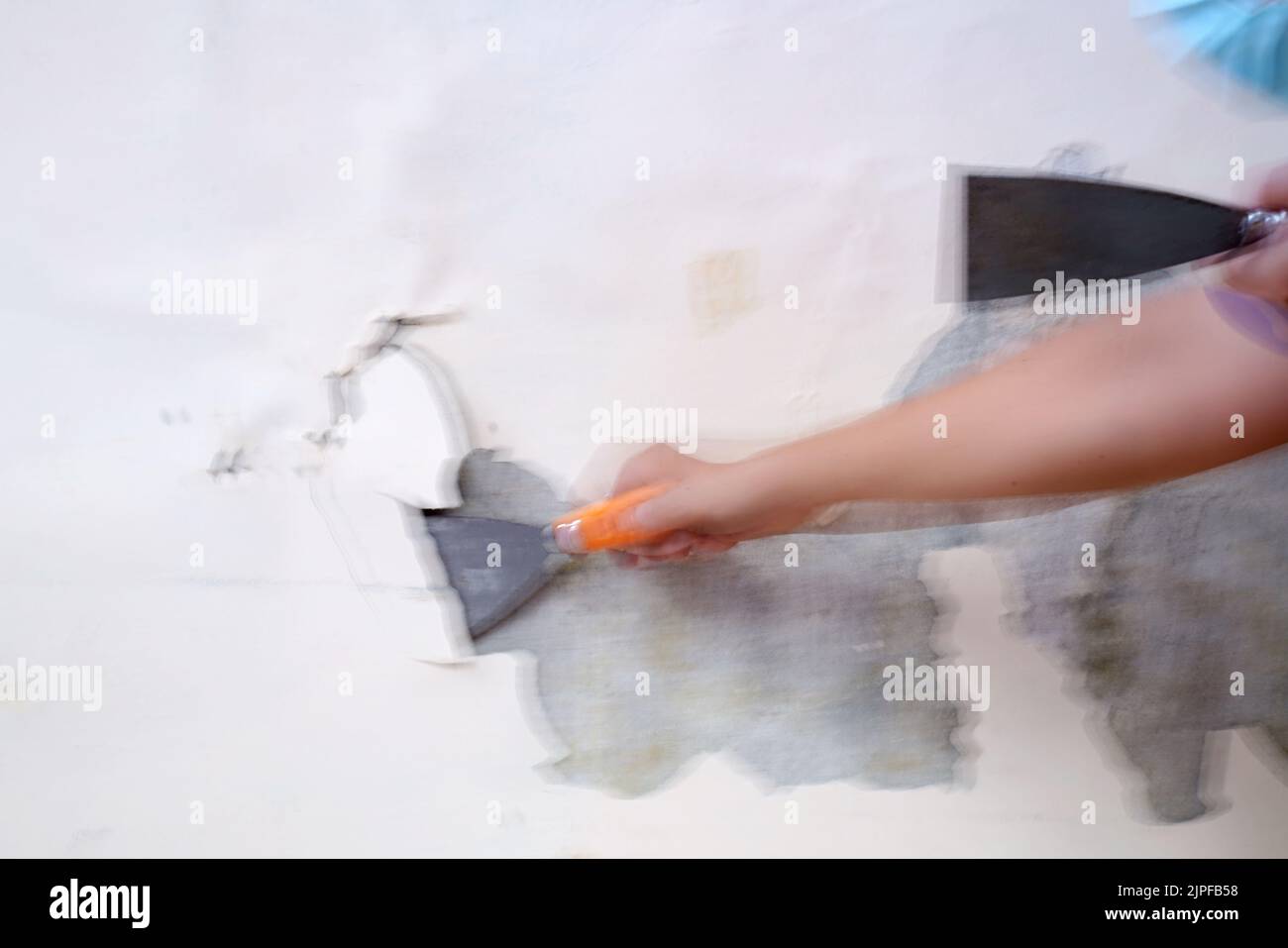 Blurry Working Concept. Removing old paint from the old wall by hand