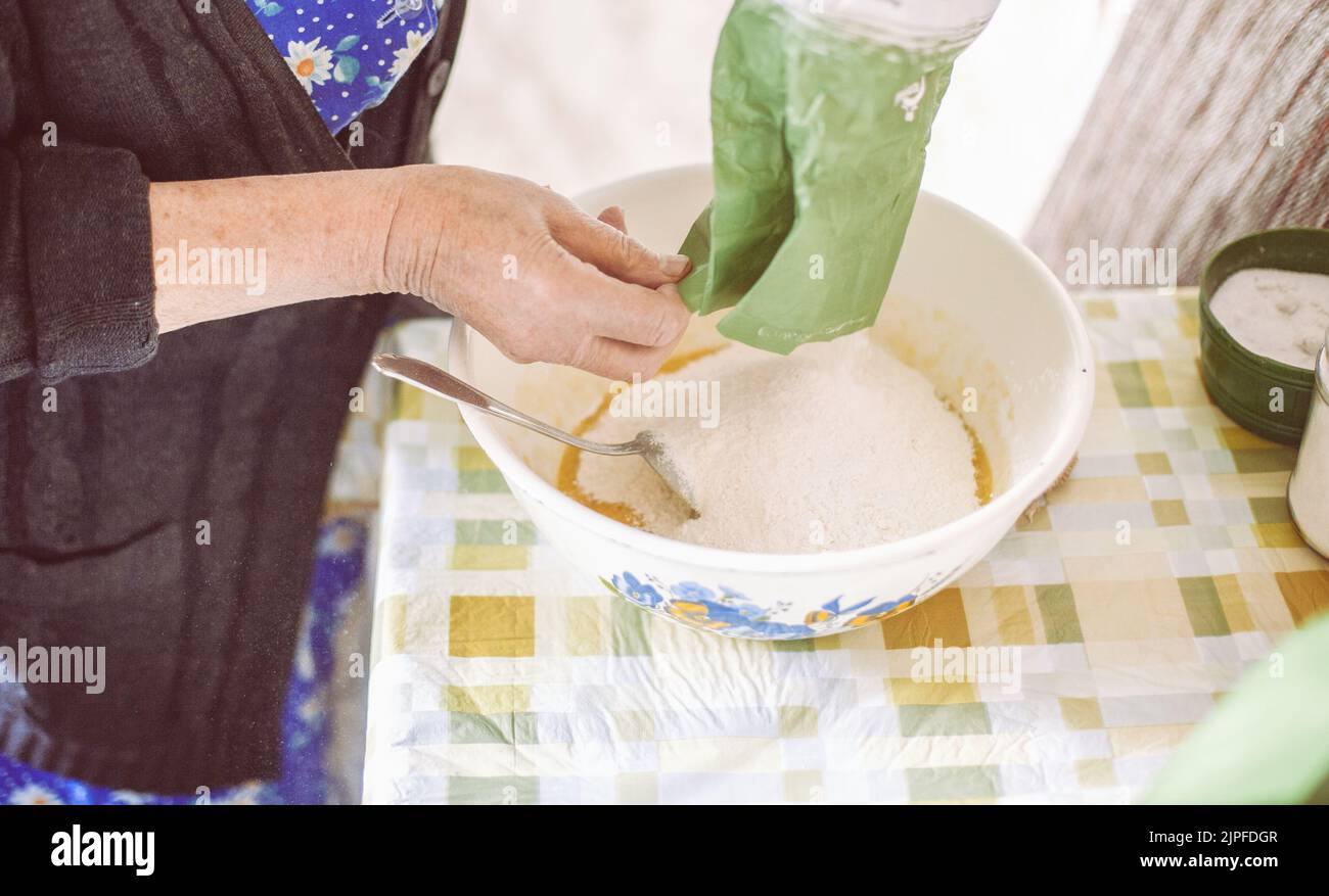 Grandmother pouring flour into pancake batter Stock Photo Alamy