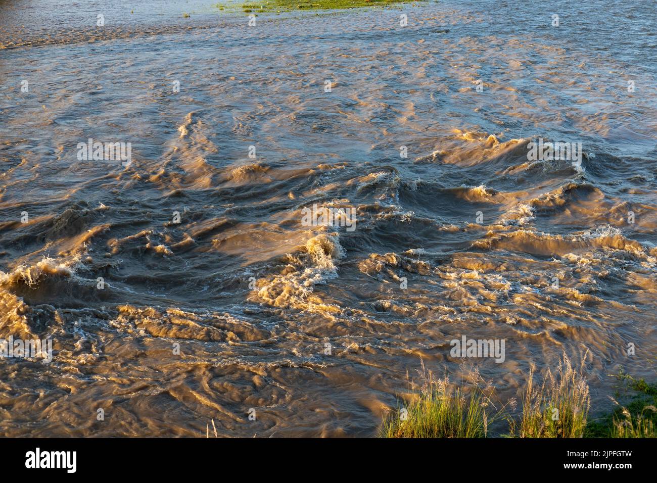 Stormy river flooding the river with muddy water and high waves Stock Photo