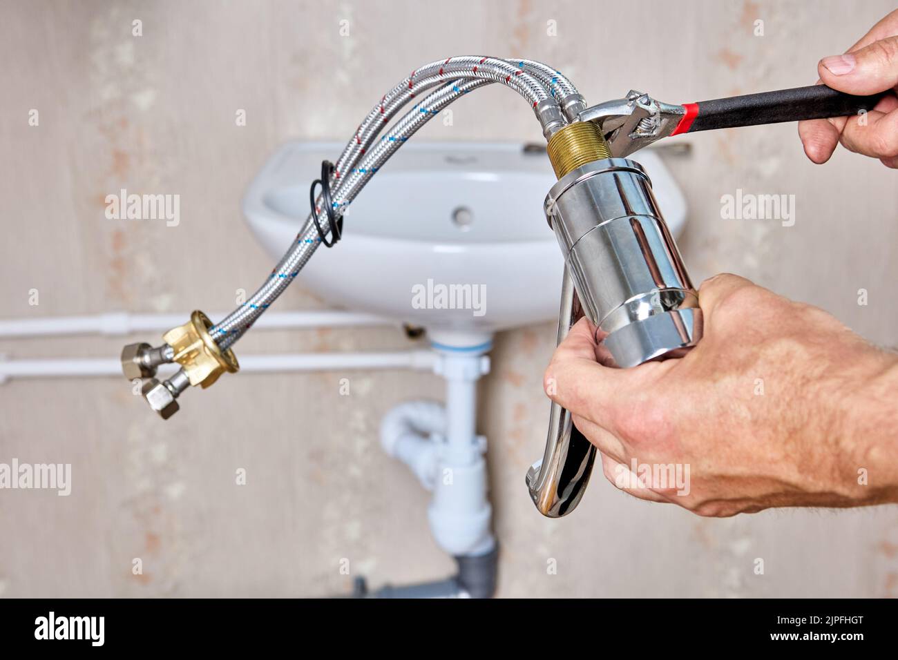 Plumber fixes connecting hoses on water faucet before installing faucet