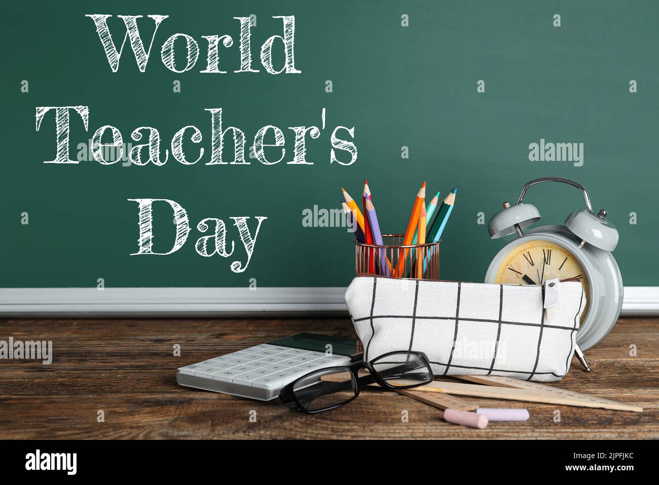 School stationery and alarm clock on table in classroom. World Teacher