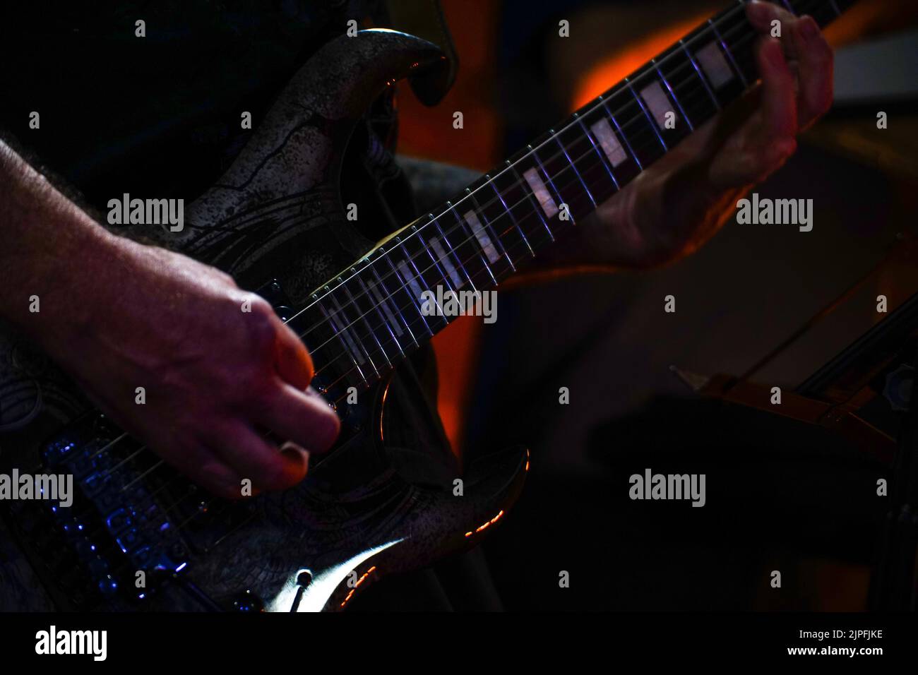 The guitarist plays on guitar in a dark room. Hands of a Guitar player