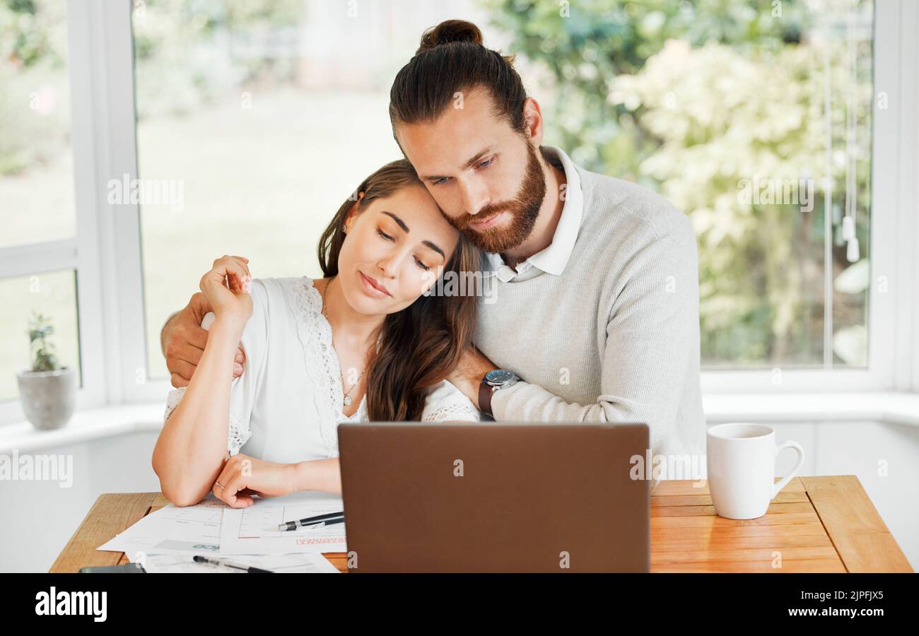 Support, couple and finances while embracing each other and sitting with papers and a laptop for bill payments and looking worried in a tough economy Stock Photo