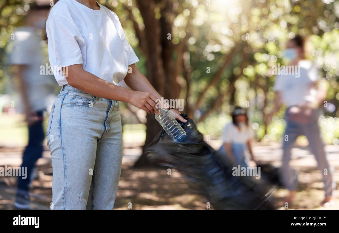 Volunteers helping collect trash on community cleanup project outdoors, collecting plastic and waste to recycle. Woman cleaning environment, picking Stock Photo
