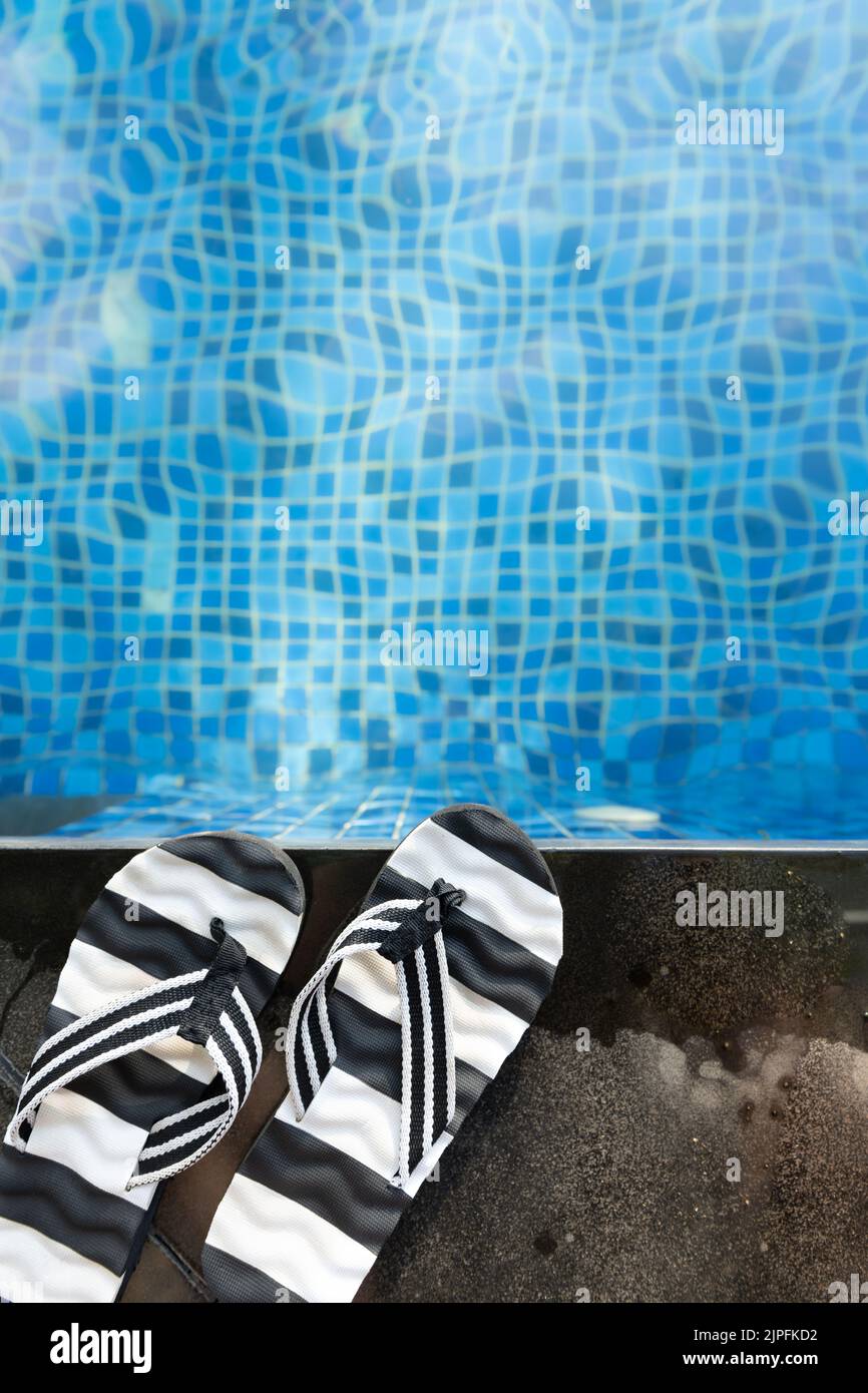 top view swimming pool and pair of slippers vertical composition Stock Photo