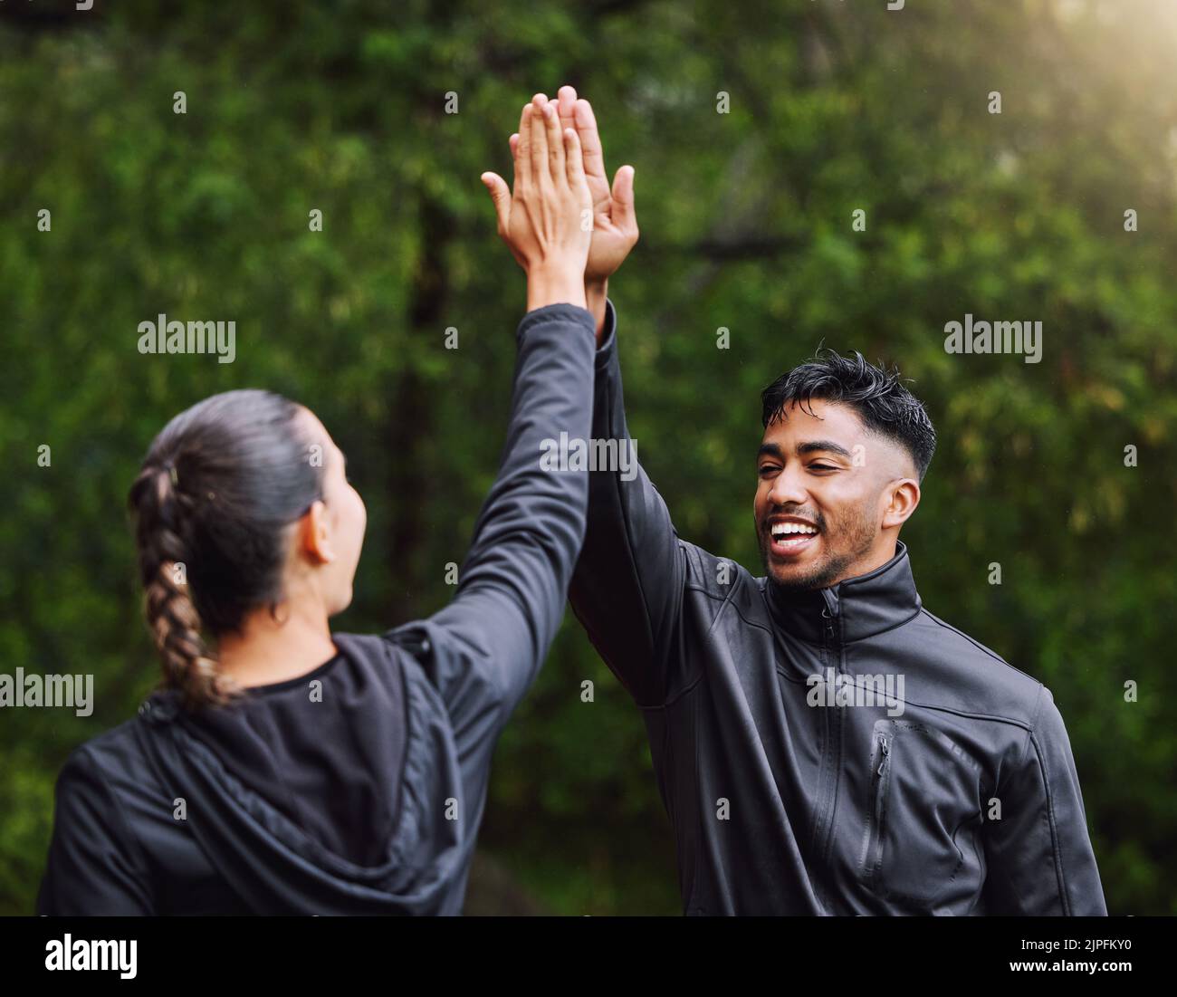 Active, fit and sporty athletes doing a high five to celebrate and congratulate on fitness goals. Healthy, happy and exercising couple motivated after Stock Photo