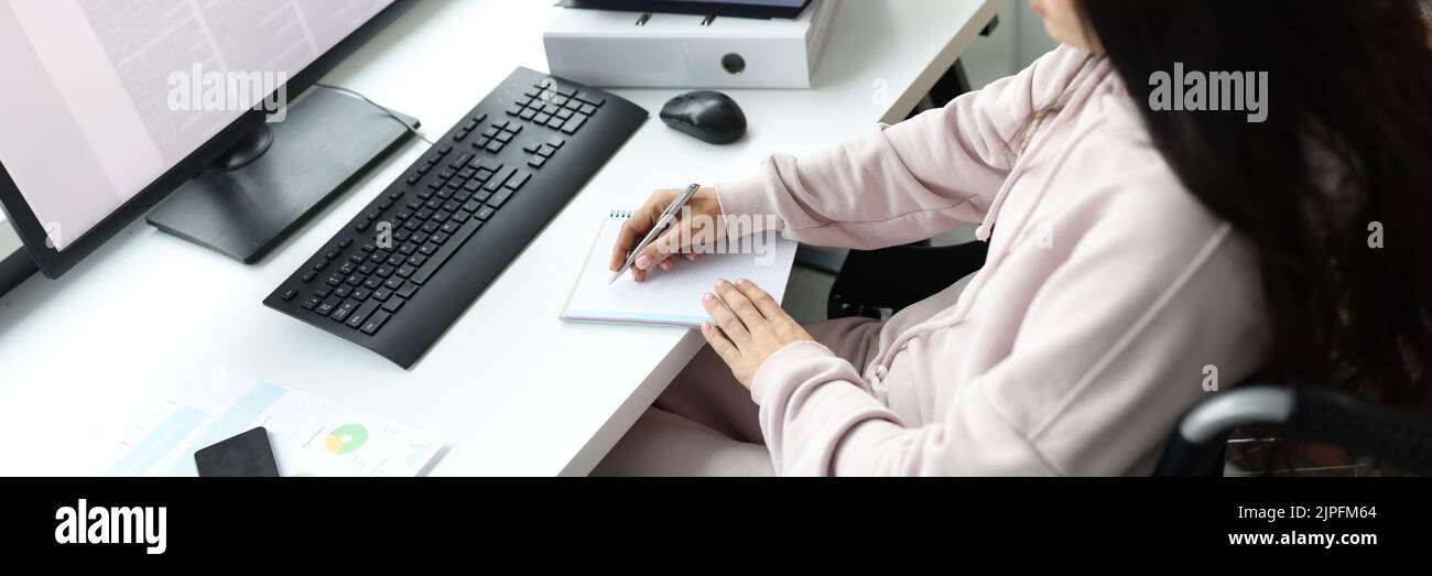 Woman in wheelchair with documents uses computer Stock Photo - Alamy