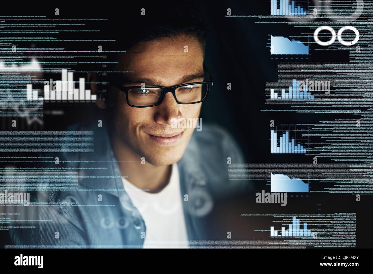 Determined to crack this code before the deadline. a young computer programmer looking through data in the dark. Stock Photo