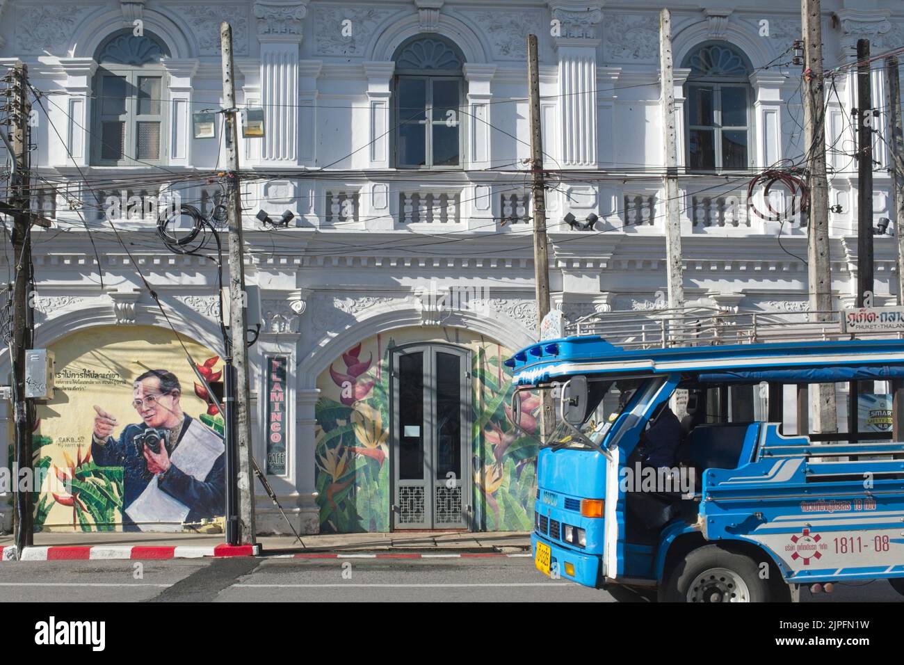 A local bus passes an old Sino-Portuguese house in Dibuk Rd. in Old Town area of Phuket Town, Thailand, with a portrait of late Thai King Bhumipol Stock Photo