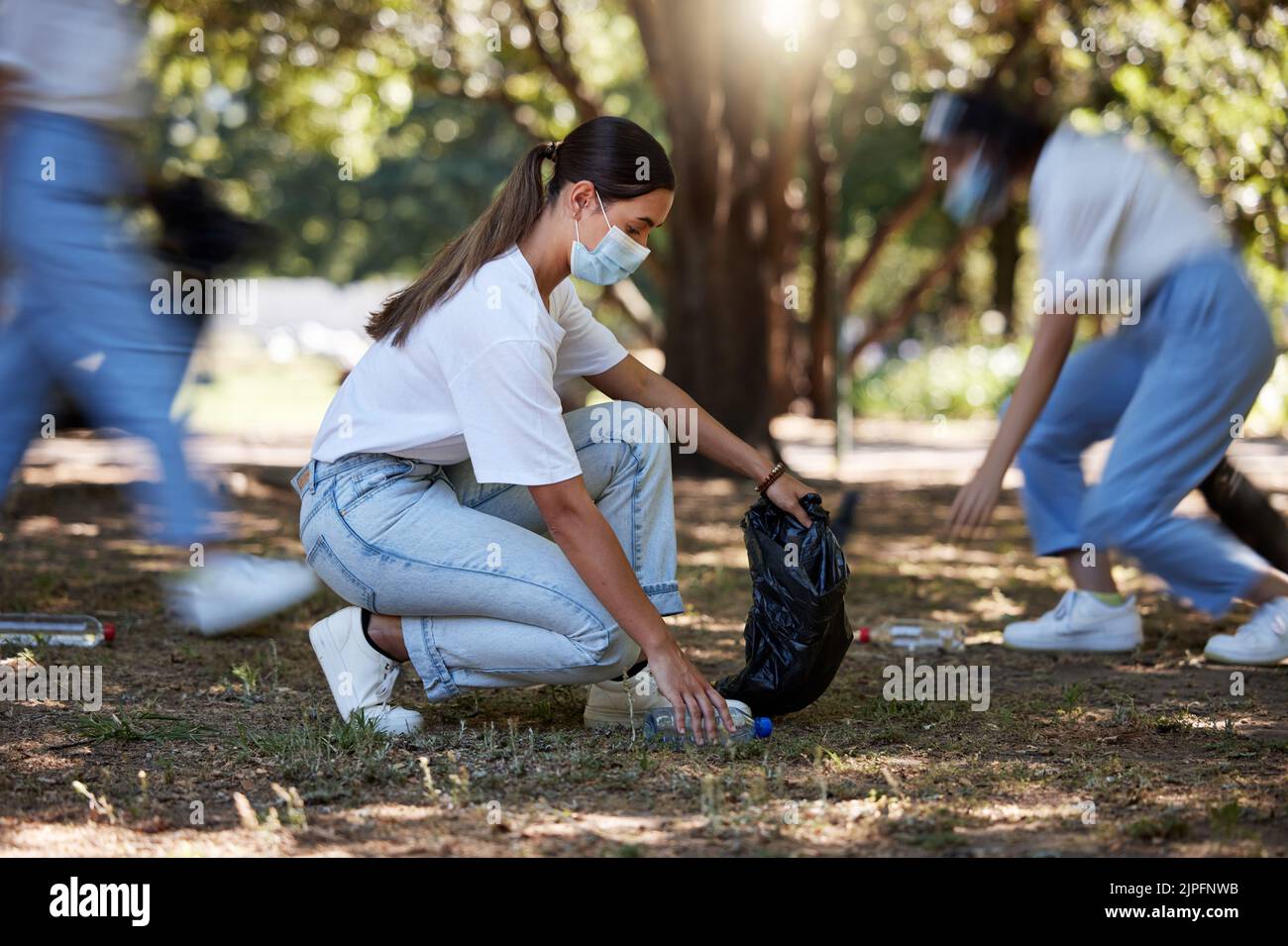 Volunteer, recycle and reduce waste by picking up litter, dirt and garbage outdoors in a park during covid. A young team of female NGO activists Stock Photo