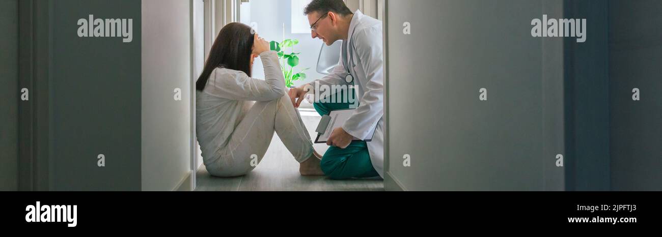 Doctor reassuring with empathy a patient sitting on the floor of a ...