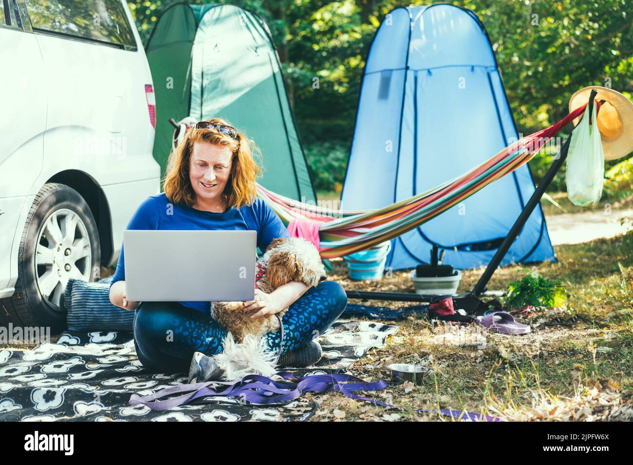 Adult woman use laptop computer sitting with her cockapoo puppy near ...