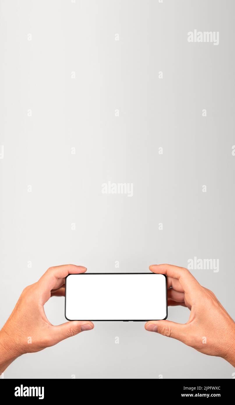 Banner with man holding phone mockup in horizontal position. Male using smartphone for watching video. Android template with blank display. Place for Stock Photo