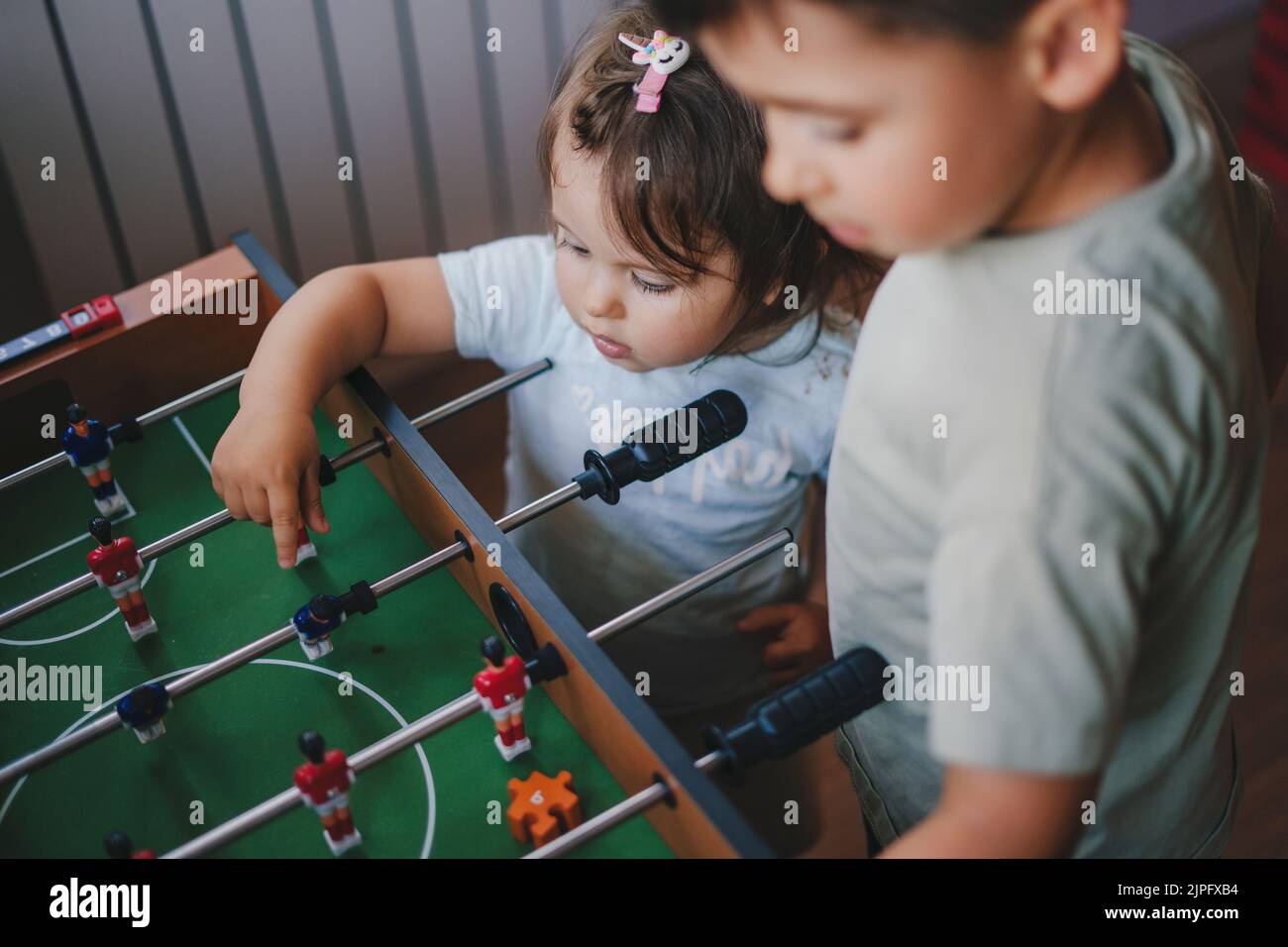 Boy and baby girl learning how to play table football. Children play table football. Games in