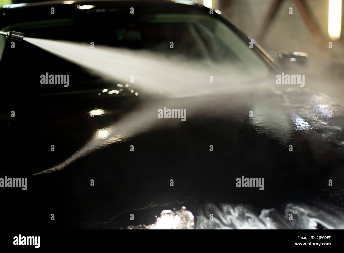 Car wash. Black car in car wash. Hot water jet. Washing off dirt from