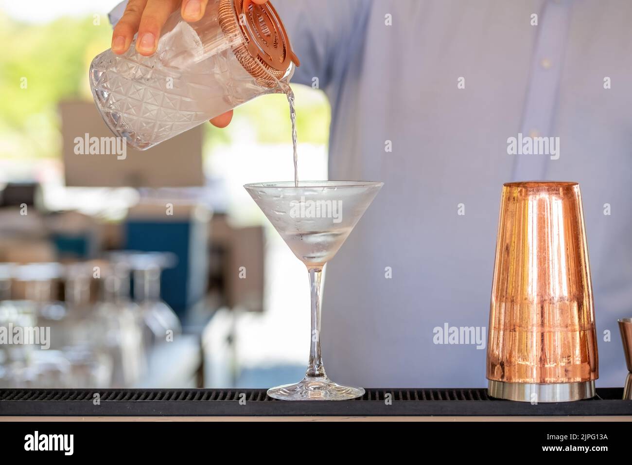 Professional bartender pouring cocktail into glass glass with shaker Stock Photo