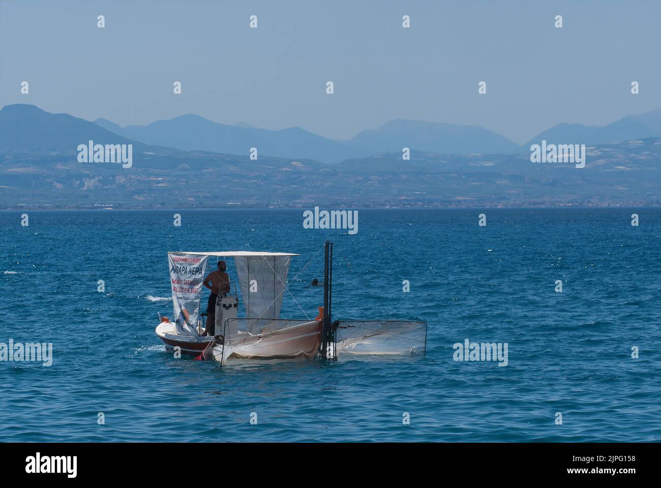 Rubbish collector in small boat in Loutraki Greece in summer Stock Photo