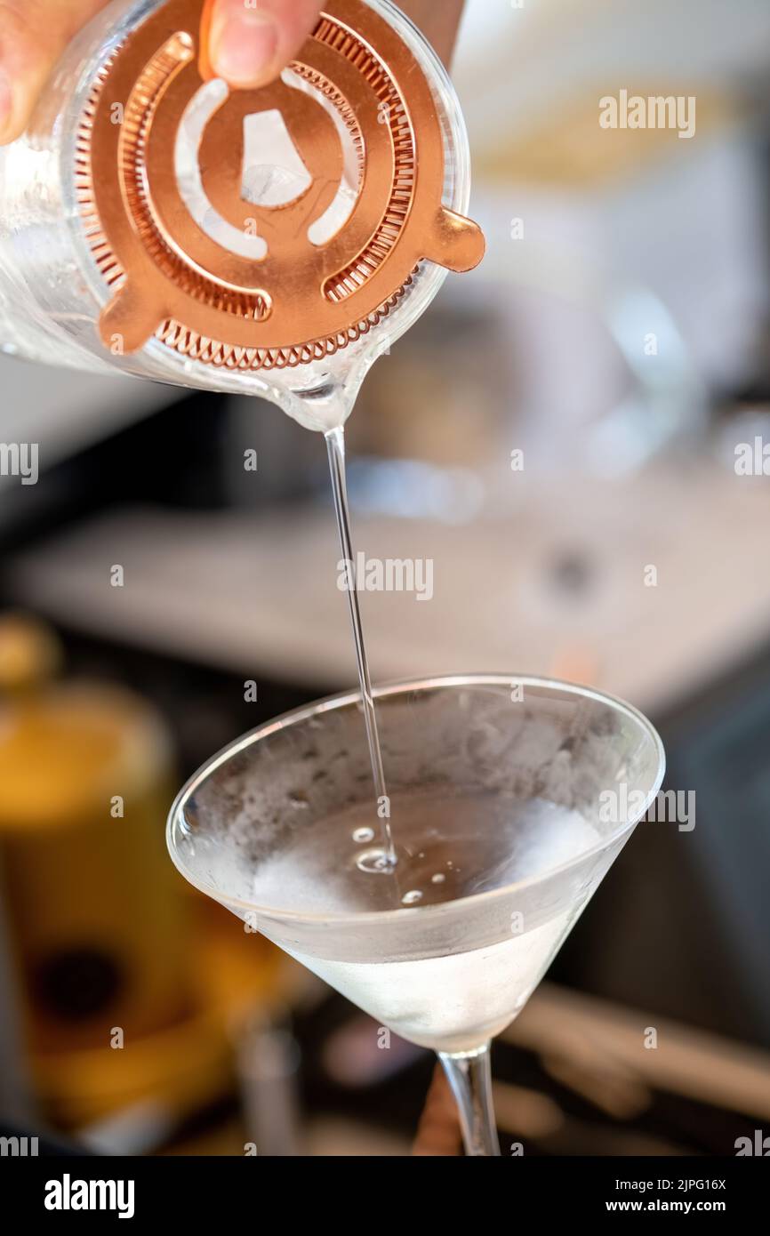 Professional bartender pouring cocktail into glass glass with shaker Stock Photo