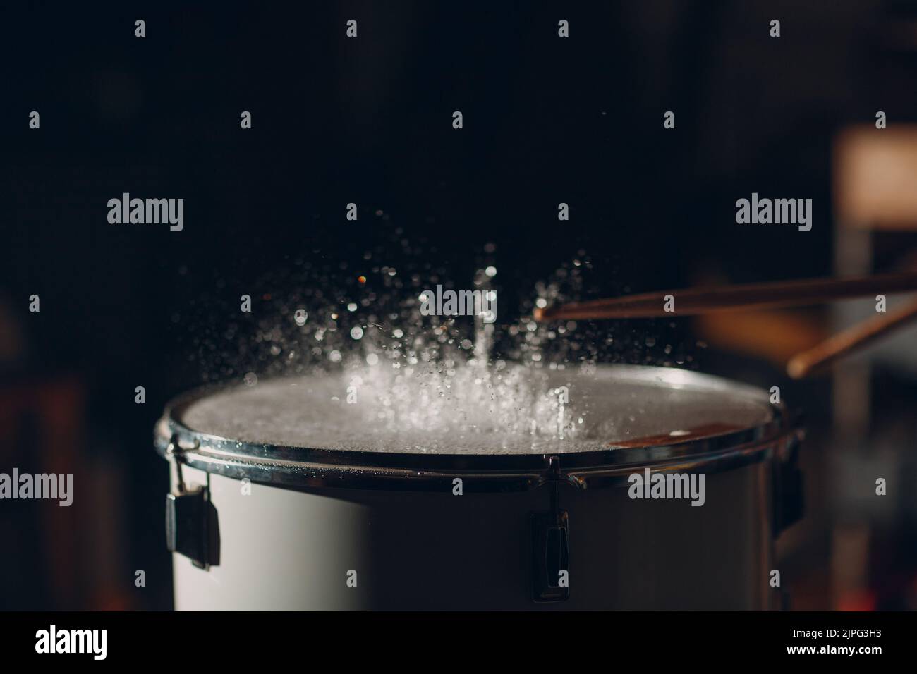 Close up drum sticks drumming hit beat rhythm on drum surface with splash water drops Stock Photo