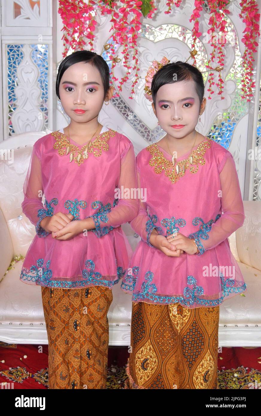 Tegal, INDONESIA - July 19, 2019: Two flower girls in pink dresses called 'Kebaya' and long Batik skirts. Stock Photo