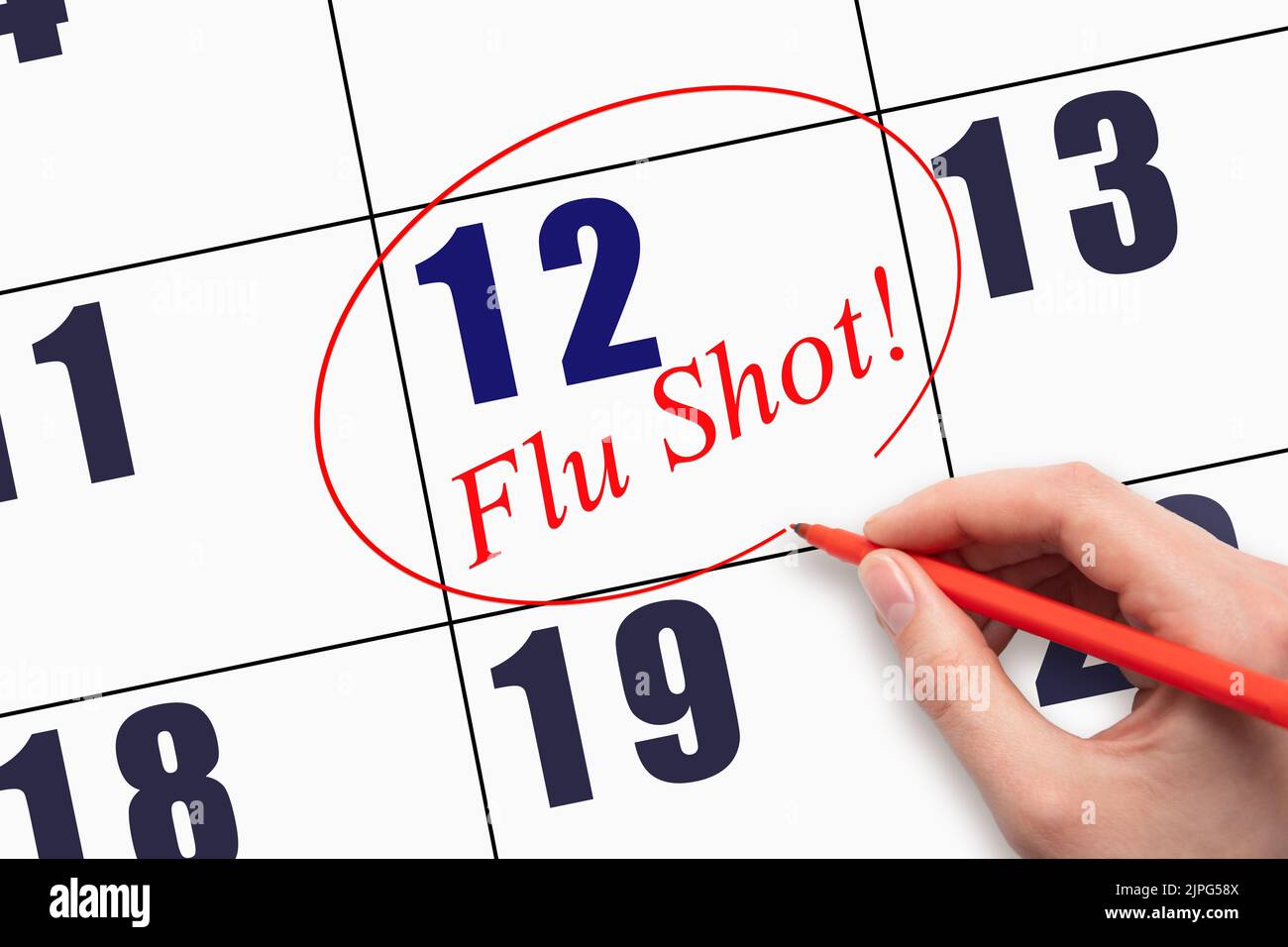 12th day of the month.  Hand writing text FLU SHOT and circling the calendar date. Mark the date on the day planner to have a flu shot. Healthcare Med Stock Photo