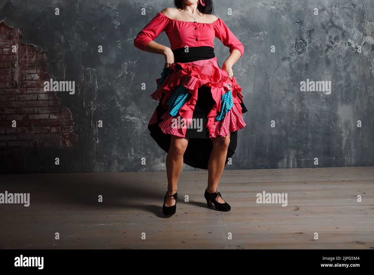 Young adult spanish woman dancing flamenco on gray vintage studio
