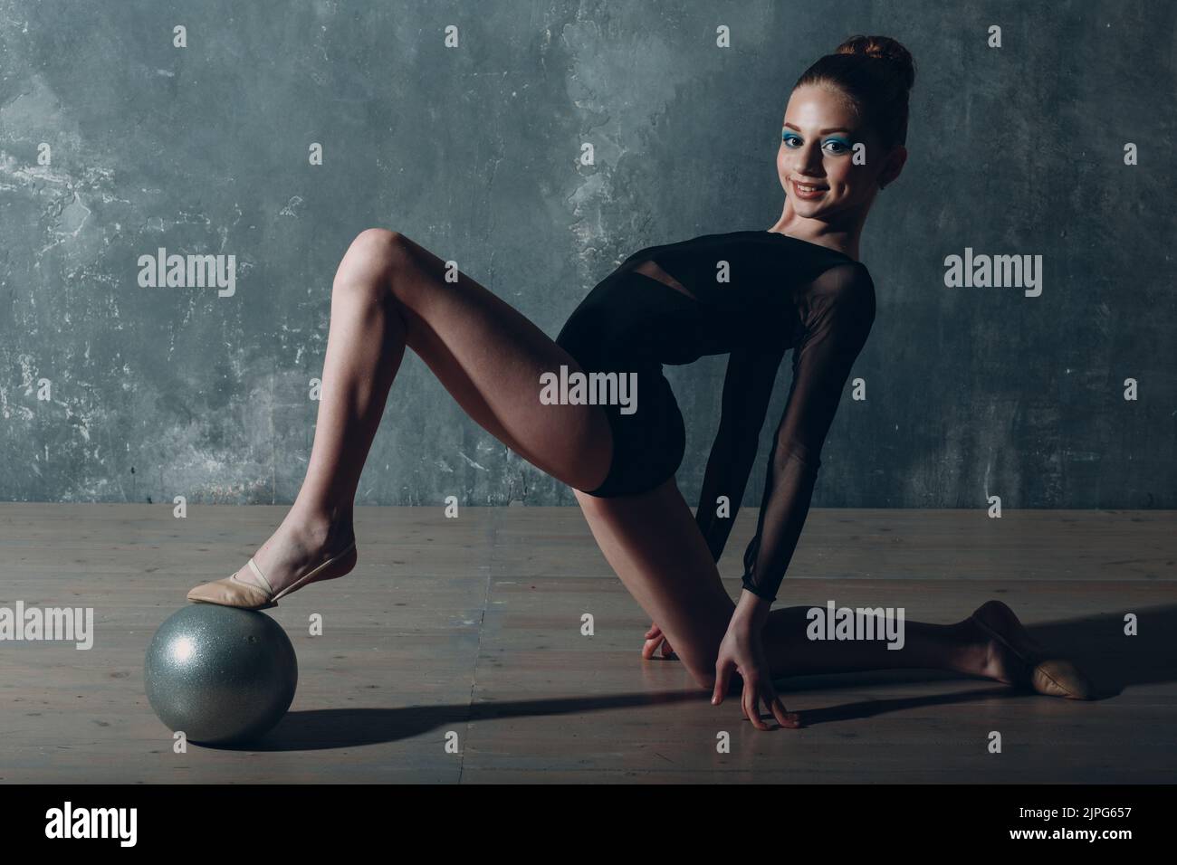 Young girl professional gymnast woman leg close up rhythmic gymnastics with ball at studio. Stock Photo
