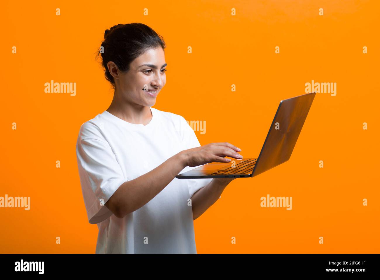 Portrait of young smiling adult indian woman working with laptop computer Stock Photo