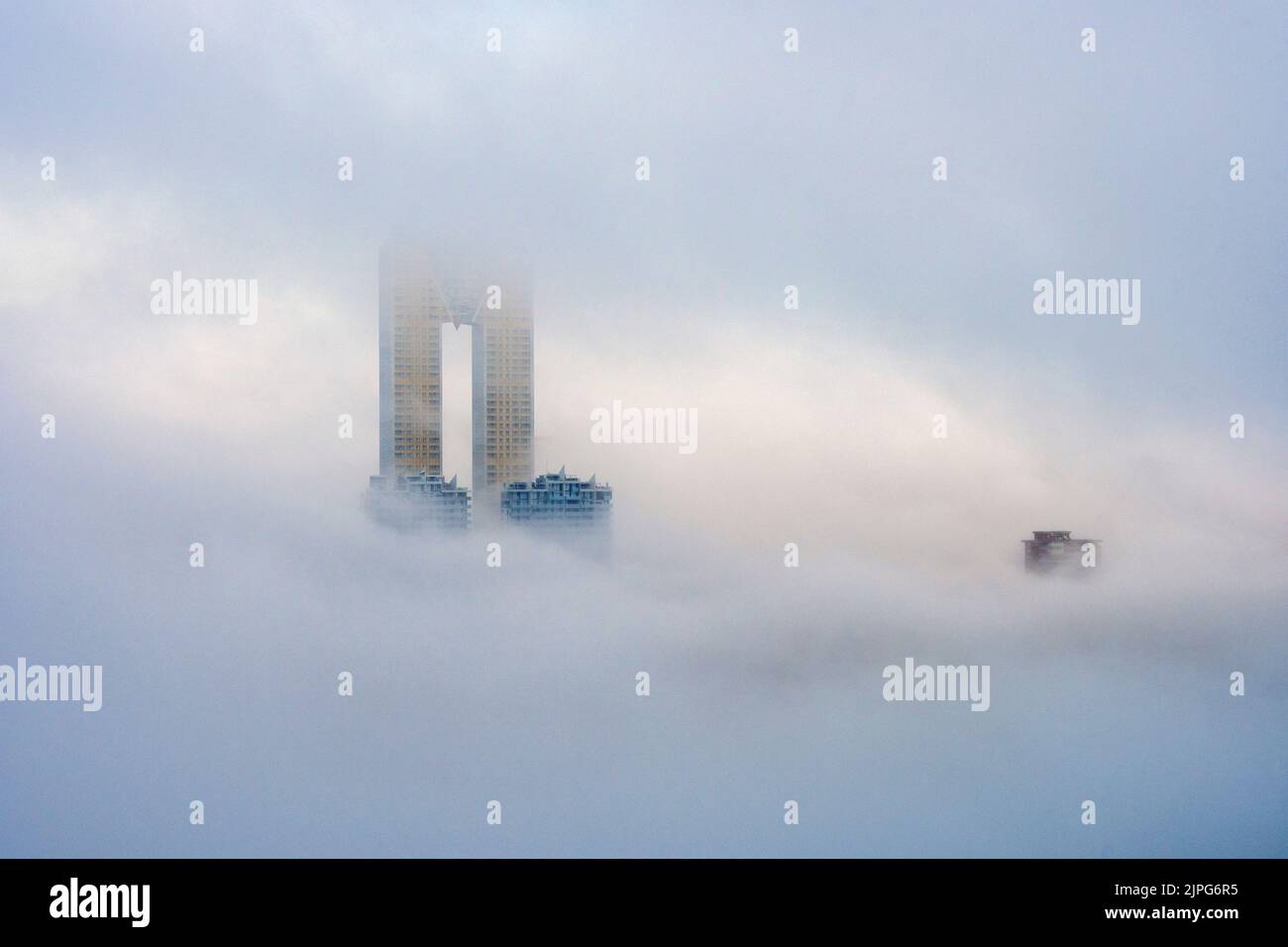 The top of the Intempo skyscraper rises above the fog in Benidorm, Spain Stock Photo
