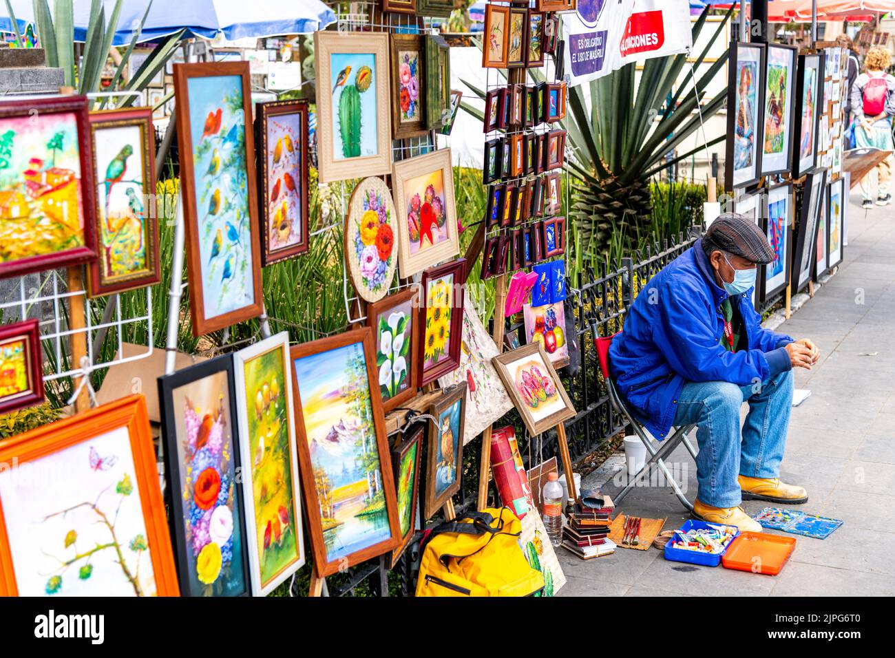 An artist sat alongside his artwork in a park in Coyoacan, Mexico City, Mexico Stock Photo