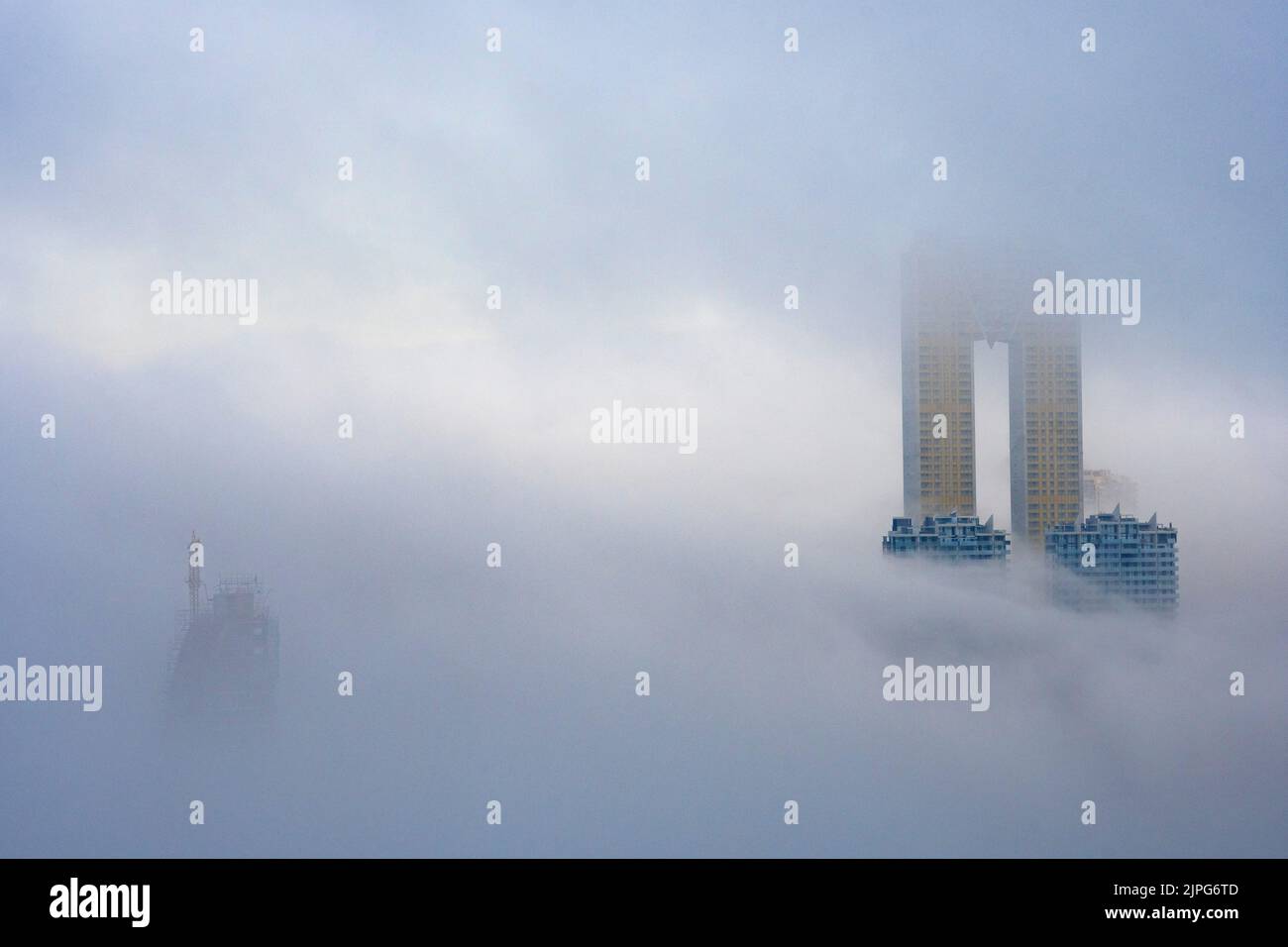The top of the Intempo skyscraper rises above the fog in Benidorm, Spain Stock Photo