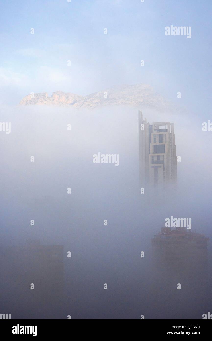 The top of the skyscraper Hotel Bali rises out of the fog in Benidorm, Spain Stock Photo