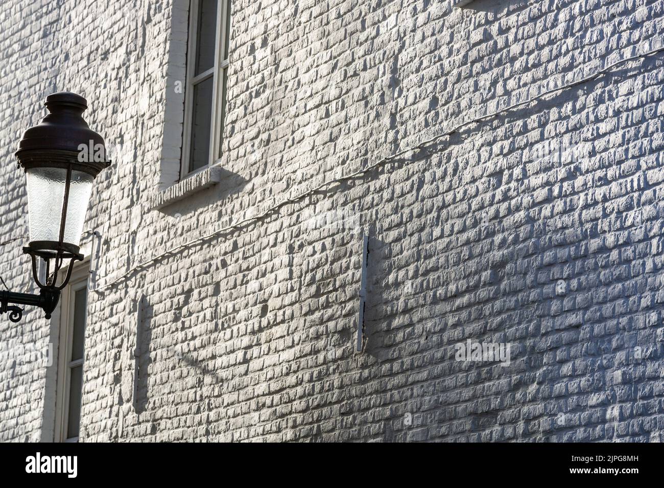 Street lamp on the background of a white painted brick wall under a