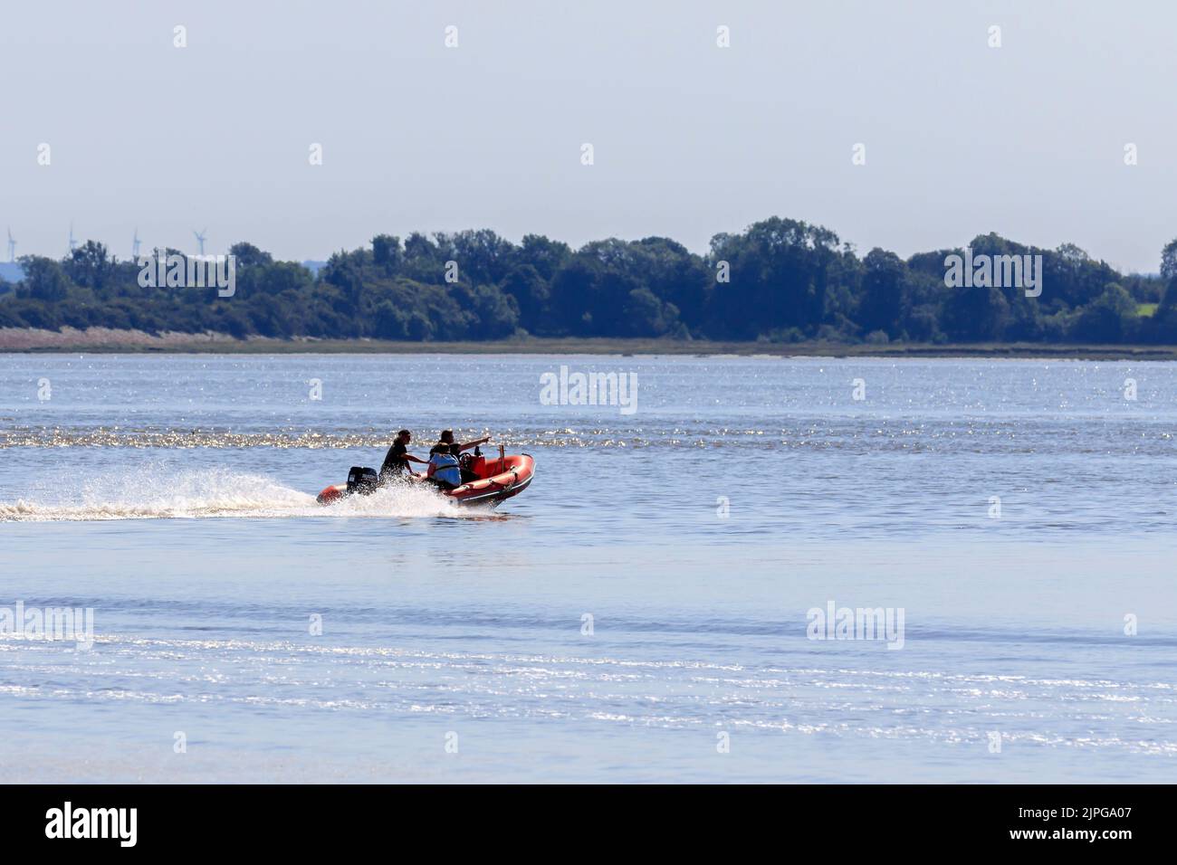 Annan, Scotland - August 12, 2022 :  Red Powered Dingy with three occupants travelling out on the Solway Firth , Scotland Stock Photo