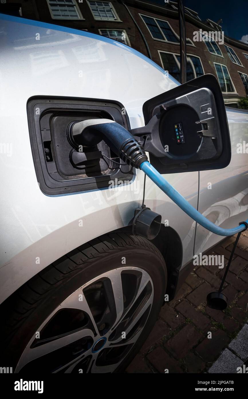 Electric car being recharged while parked on street Stock Photo