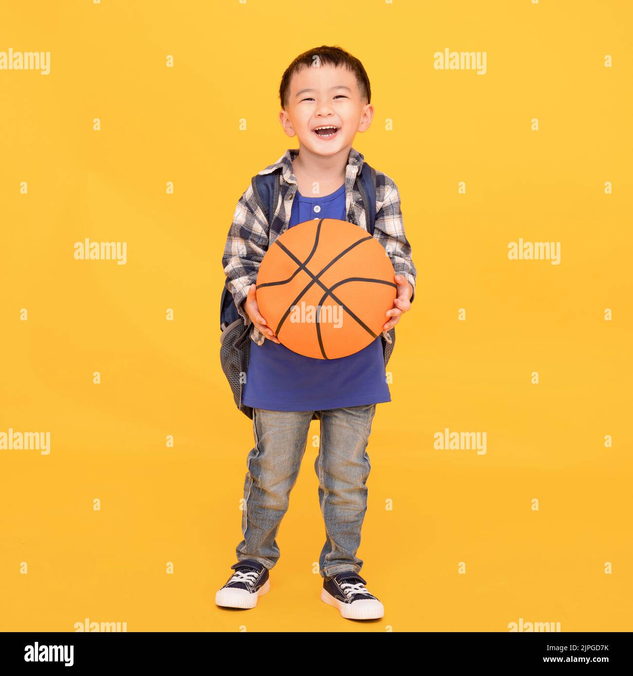 Happy smiling  boy  holding  basketball isolated on yellow background Stock Photo