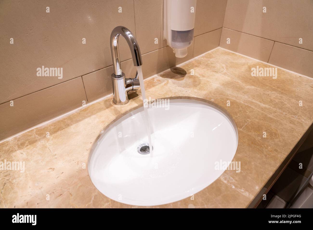 Water flows from a faucet into a sink in a modern interior Stock Photo Alamy
