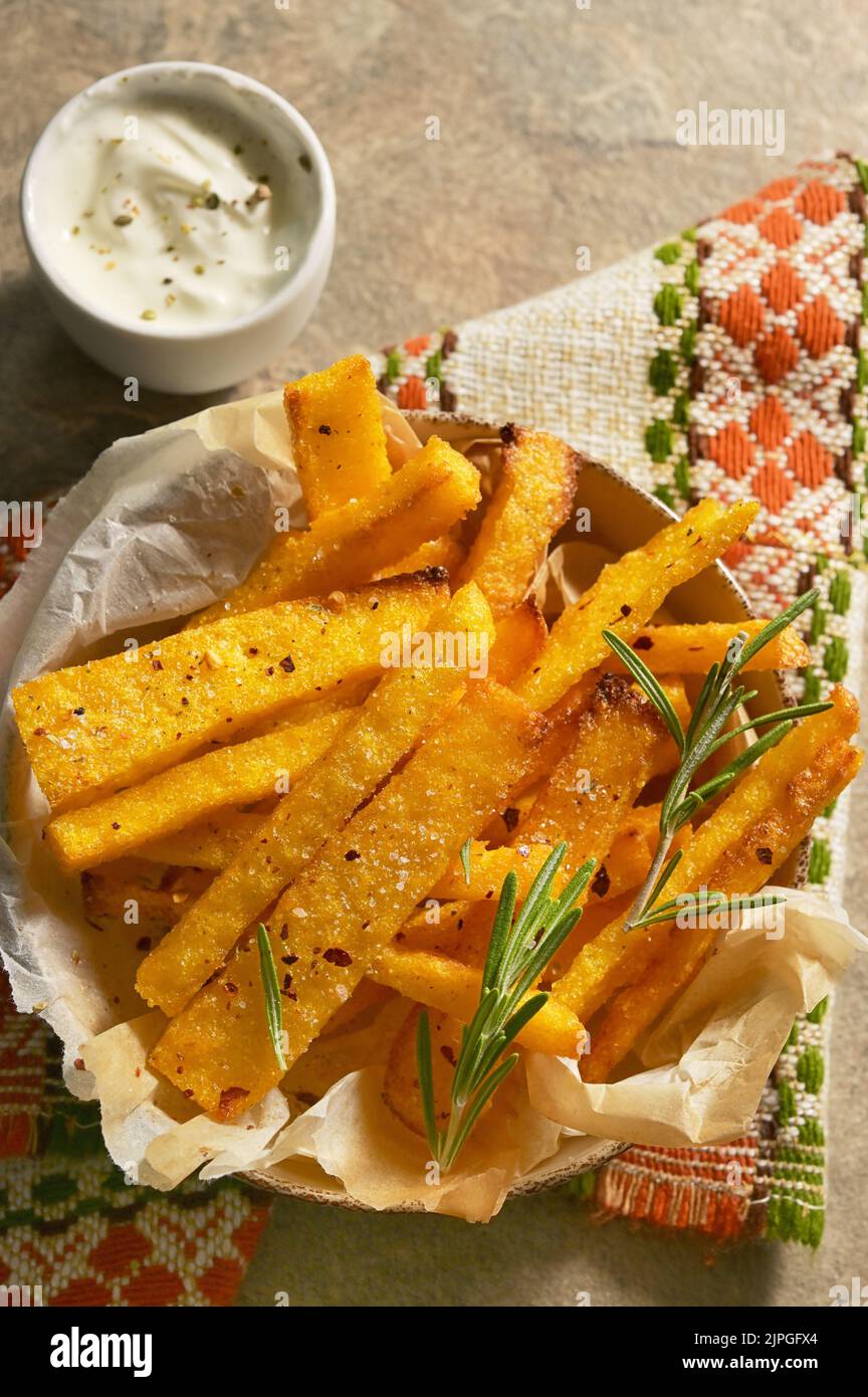 Homemade polenta fries with thyme, rosemary and yogurt sauce Stock Photo