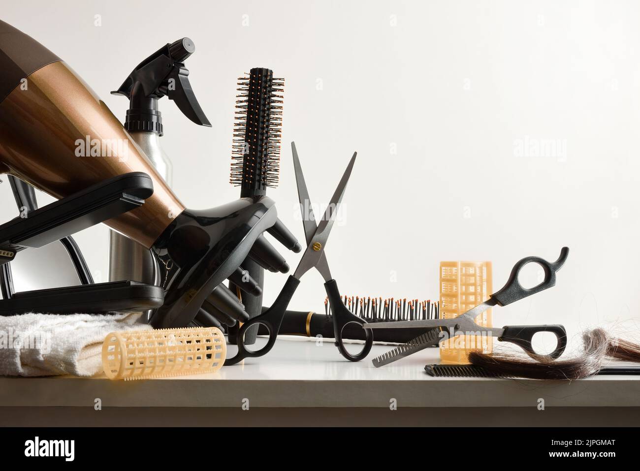 Hairdressing tools on white workbench with white isolated background. Front view. Horizontal composition. Stock Photo
