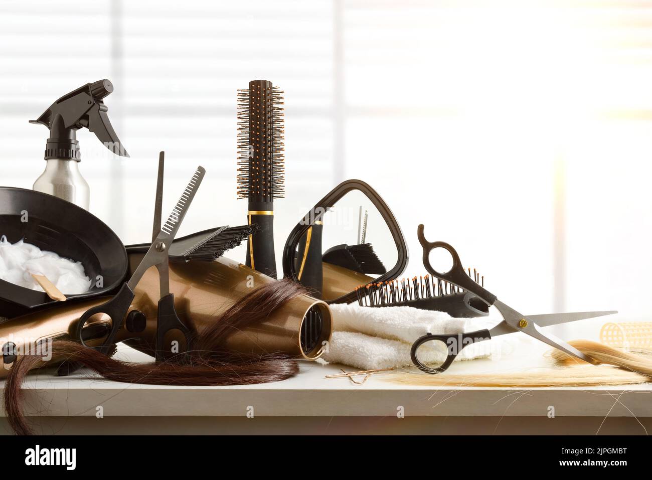 Hairdressing accessories on white workbench in hairdressing salon with window in the background. Front view. Horizontal composition. Stock Photo
