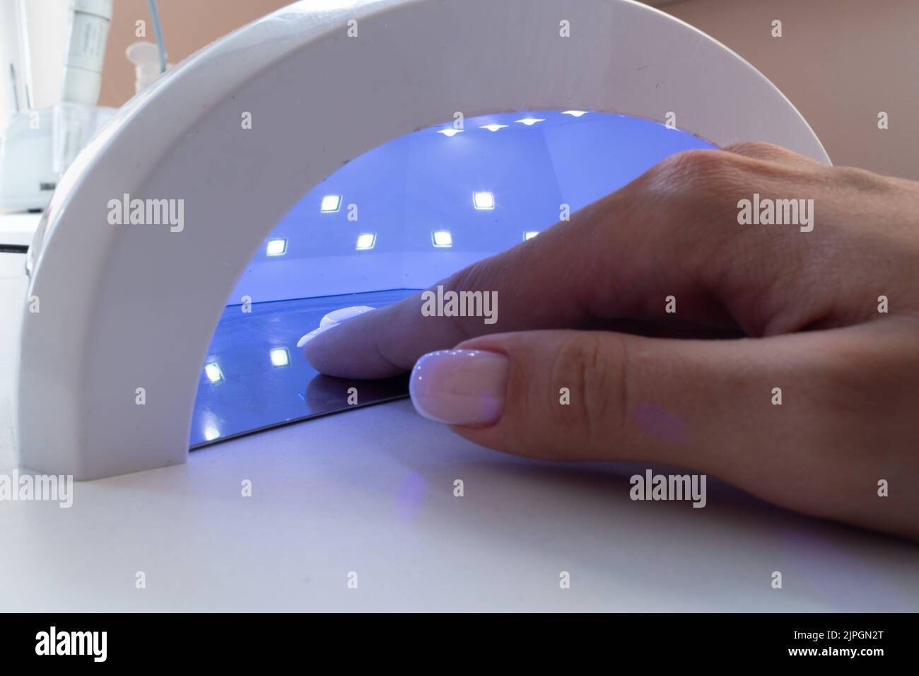 Female hand inside drying UV light machine in nail salon Stock Photo
