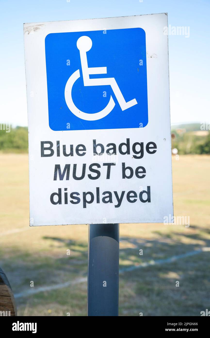 Close up of sign by disabled parking space at UK sports field advising blue badge holders that blue disability permits must be displayed in vehicles. Stock Photo