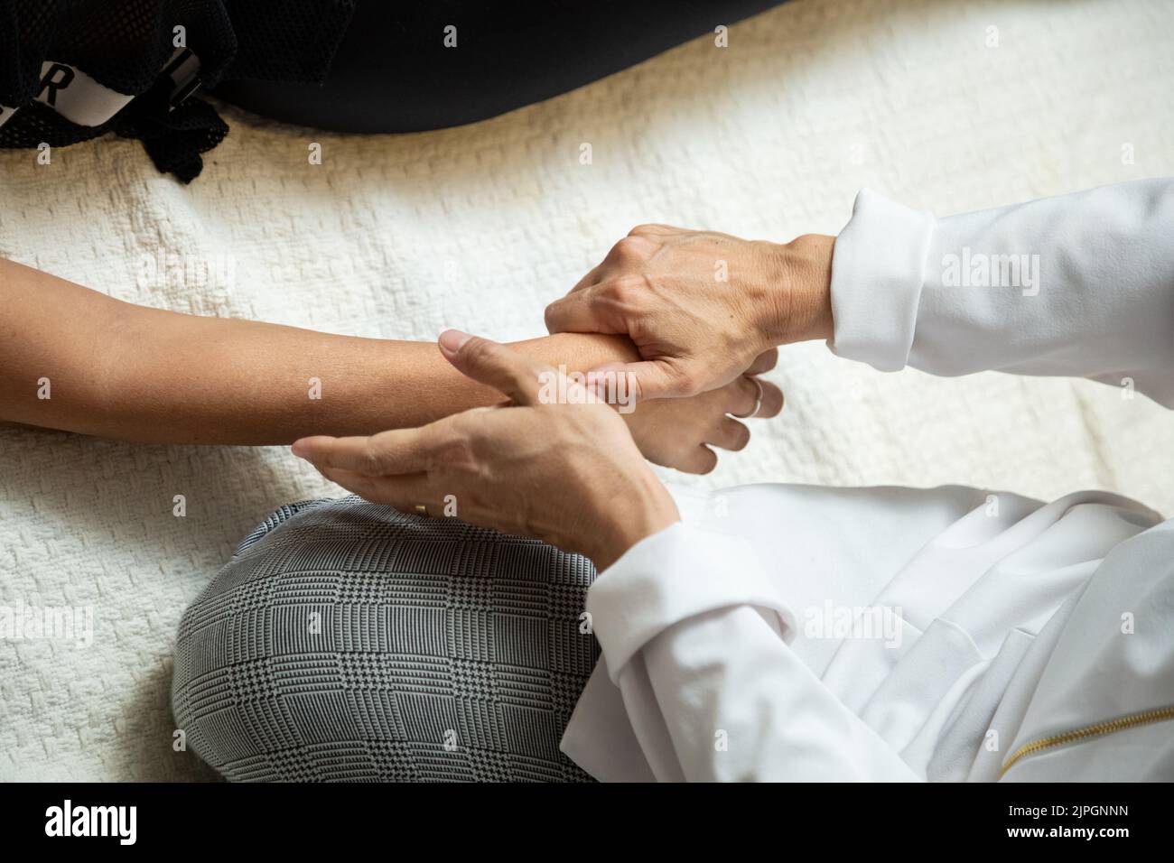 Goiânia, Goias, Brazil – July 18, 2022: Closeup of hands of masseuse, applying therapeutic massage on the hand of a patient who is lying down. Stock Photo