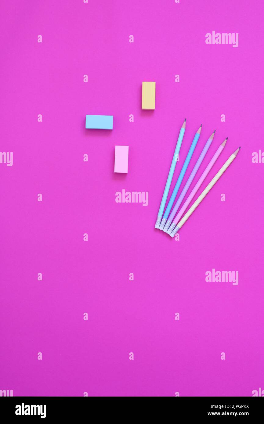 top view of pastel colored pencil and eraser on bright pink background ...