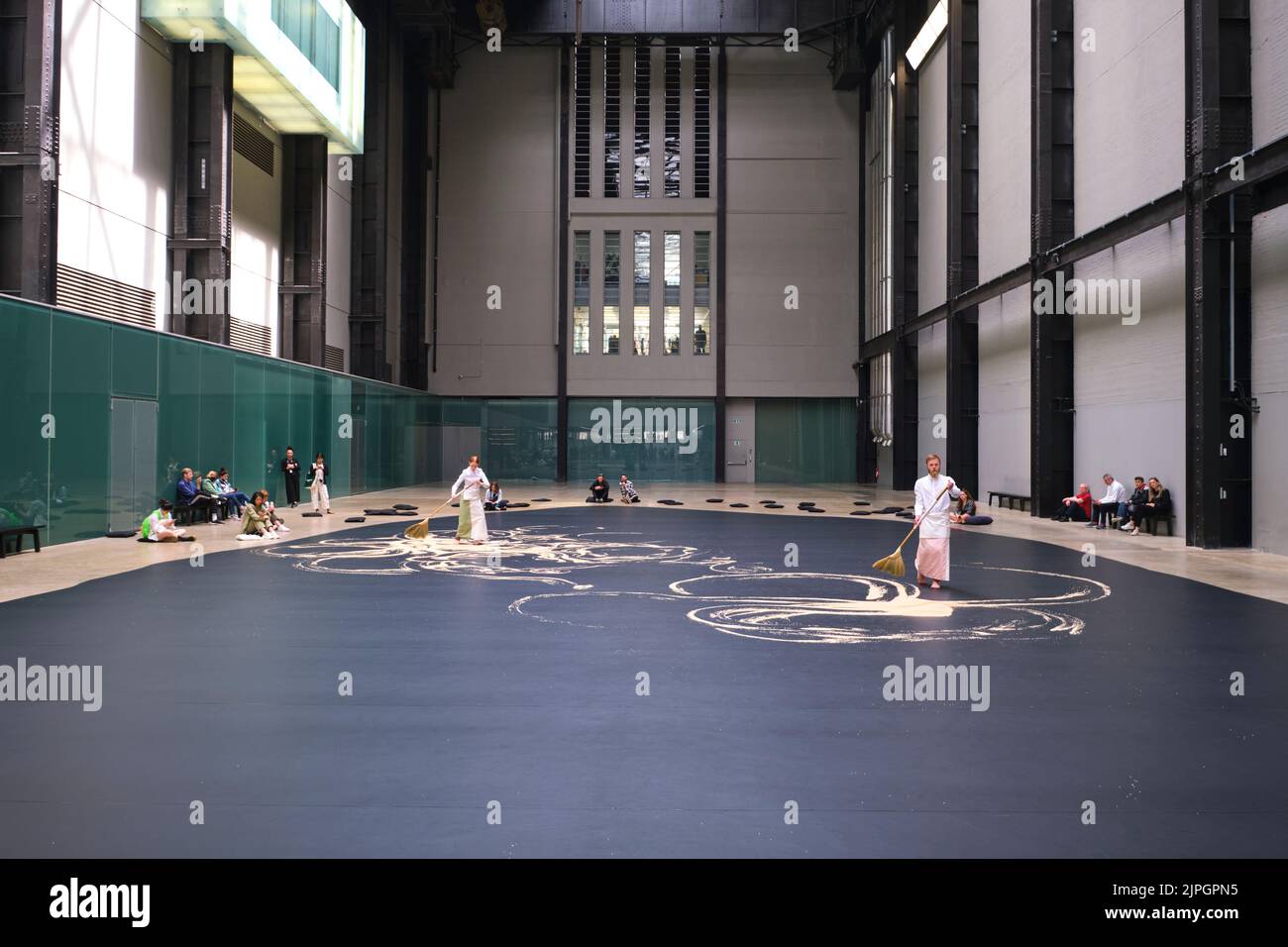 Performers in traditional dress push rice with brooms in a work titled, 'Labyrinthine', by artist Lee Mingwei. At the main hall of the power station b Stock Photo