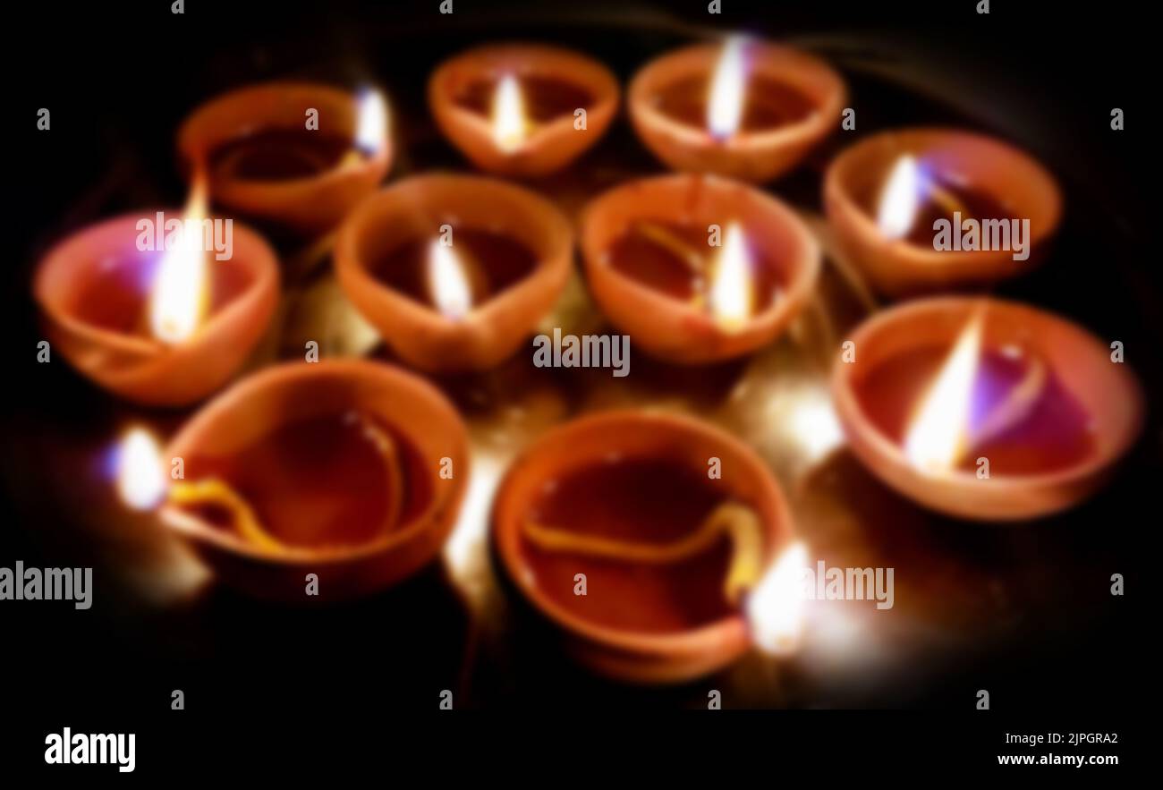 A Blurred Macro shots of diyas being lit by hand or candle for the hindu religious festival of Diwali Stock Photo